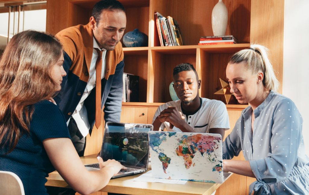 People gathered around a table working together on laptops during a group discussion