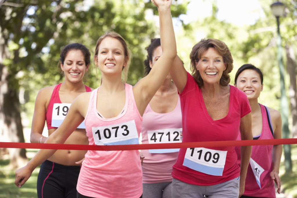Group of women hold hands as they cross the finish line of a running race