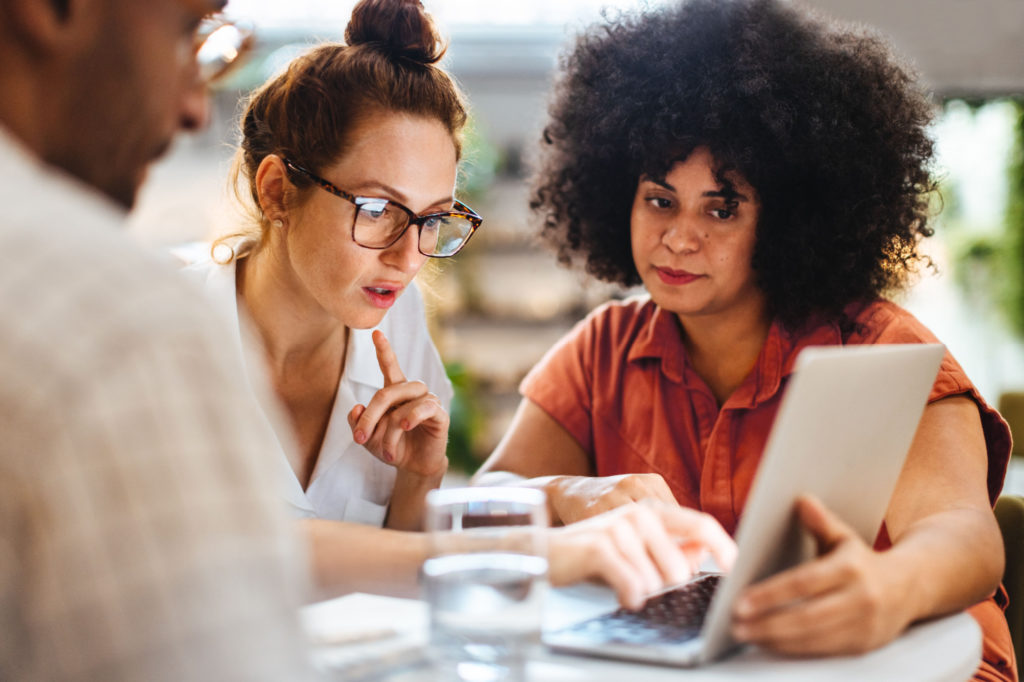 Women sit around a laptop