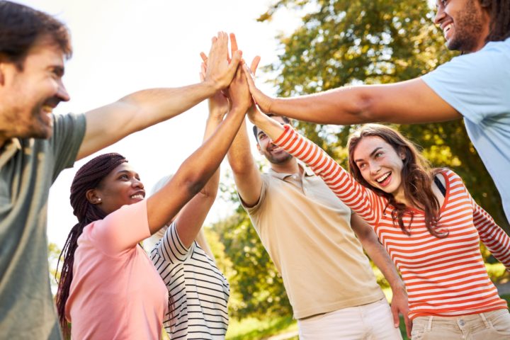 Group of people stand in circle joining hands in centre