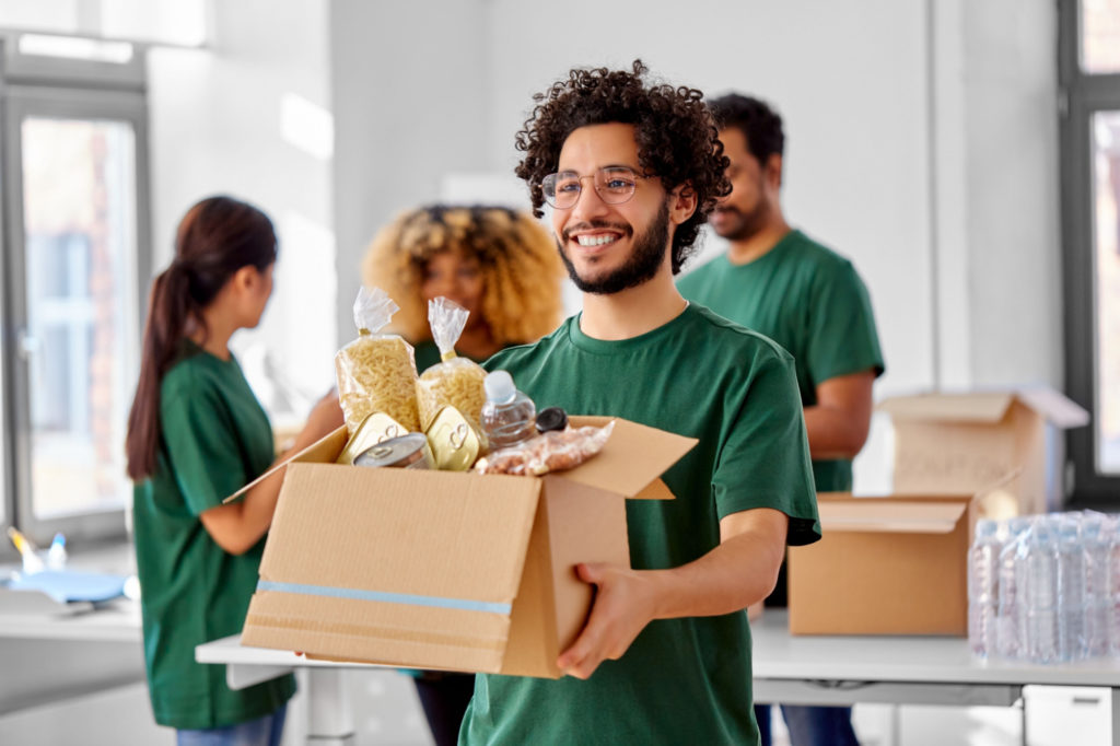 Young man in green t-shirt carries box of goods