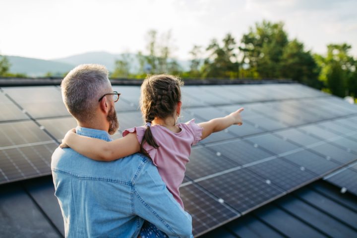 Man holds young girl pointing at solar panels