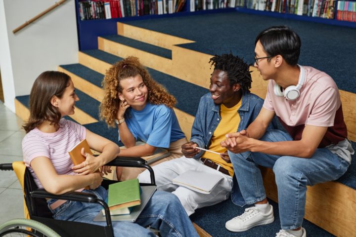 Group of smiling diverse people sit next to and on steps
