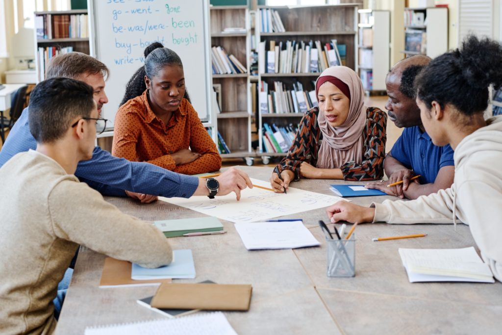 Group of people seated around a table working together on documents during a discussion