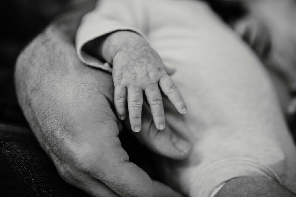 Close-up of a baby’s hand resting on an adult’s hand