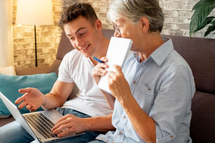 Young man sitting with laptop he's showing to older woman