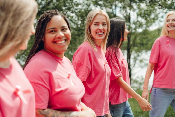 Group of happy smiling women gathered outside in a meadow near a river
